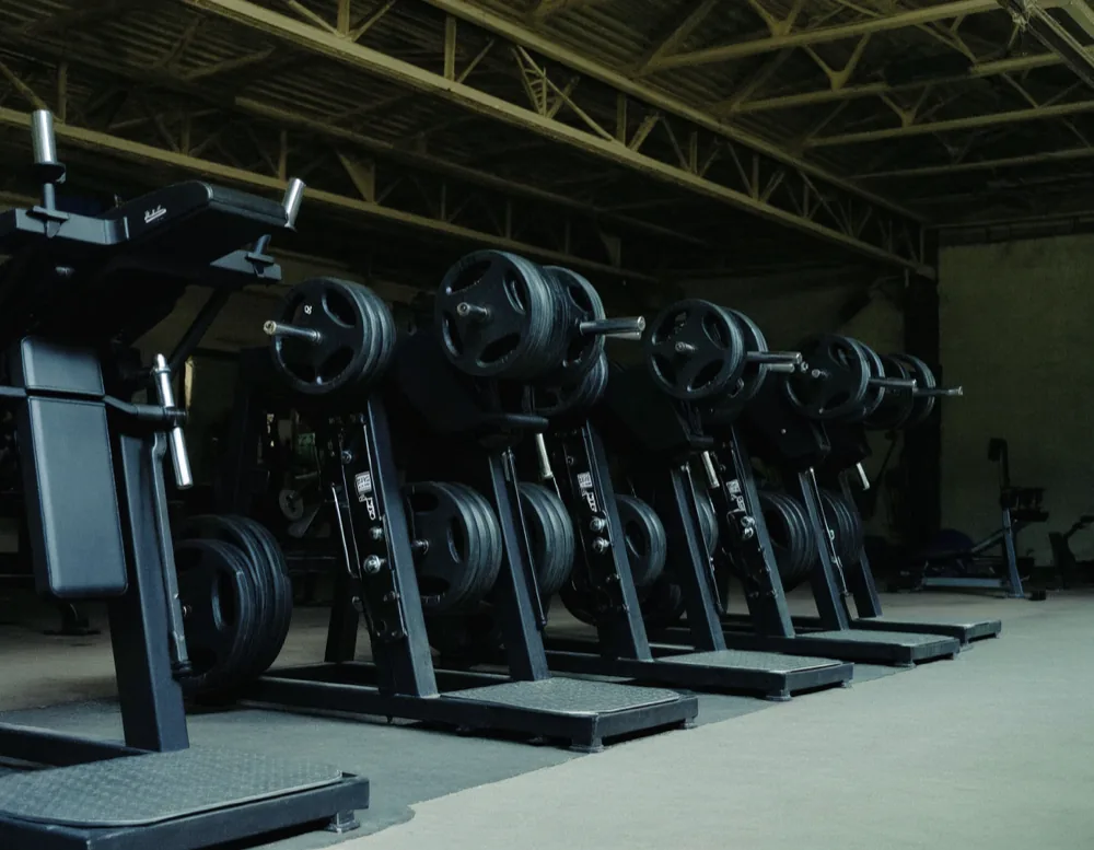 A row of black plate-loaded machines with cast iron plates on the pins under a steel roof truss.