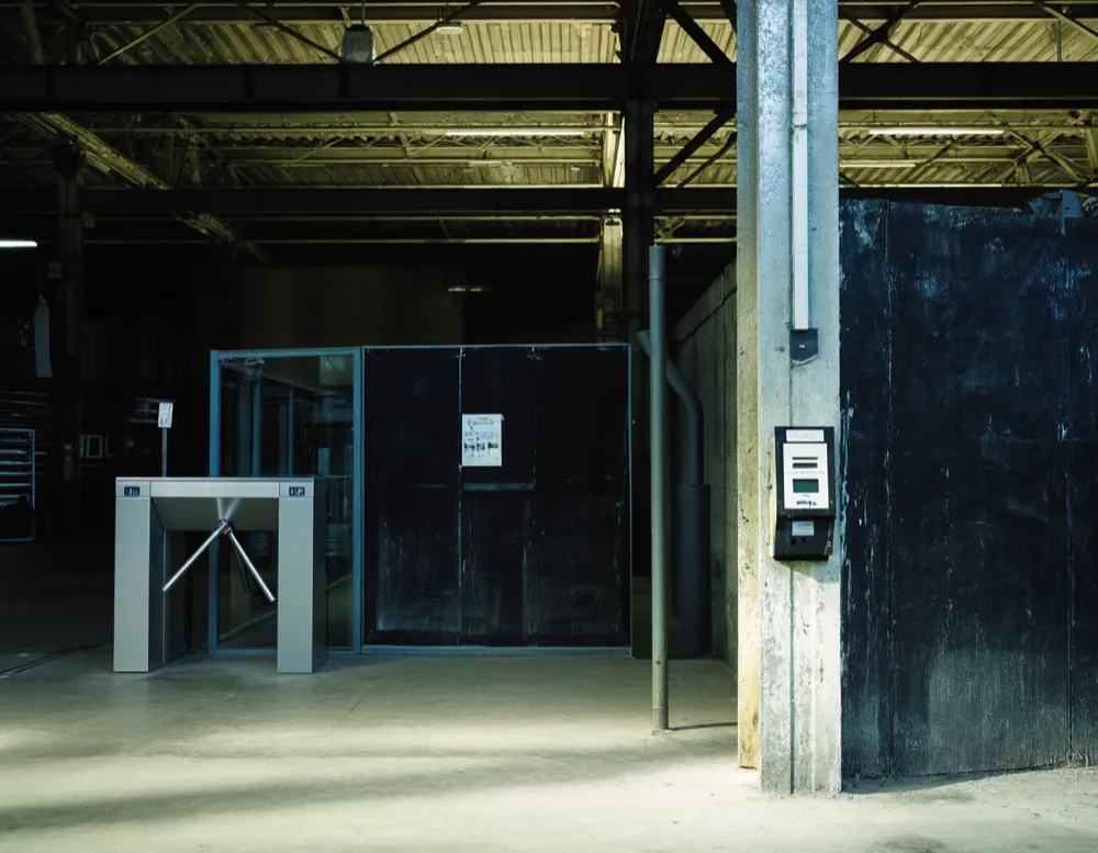 The plain entrance of the gym: a bare steel turnstile and a card reader beside a glass door.